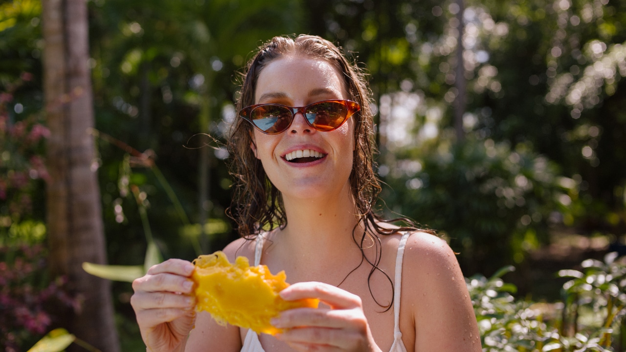 Woman eating fruit and wearing sunglasses outside