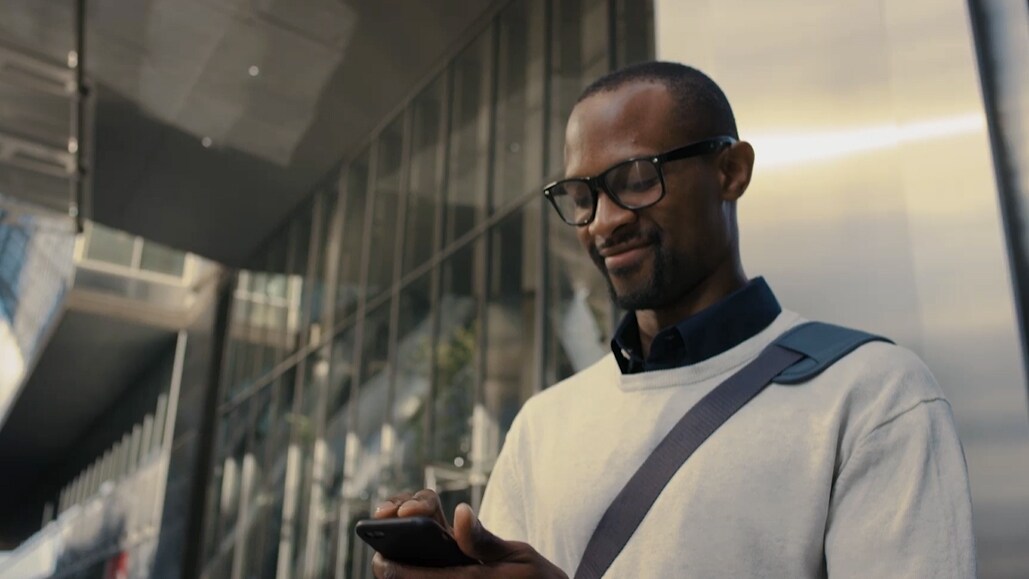 Man looking at his phone in front of a building.