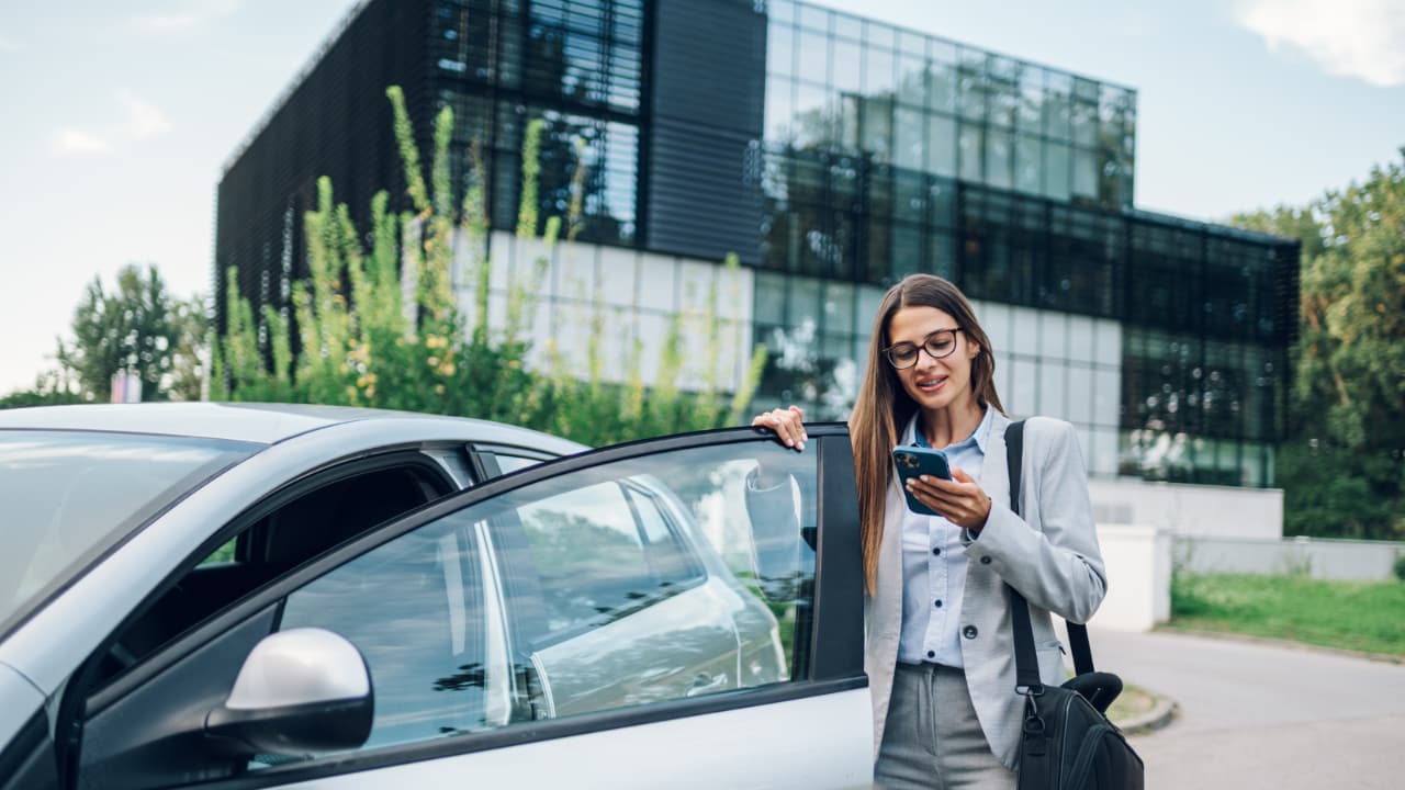 Woman on her phone getting into a car.