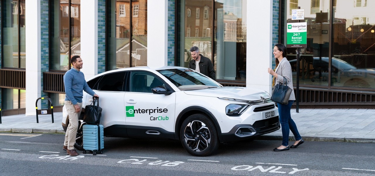 3 people getting into a white Enterprise Car Club Rental Car
