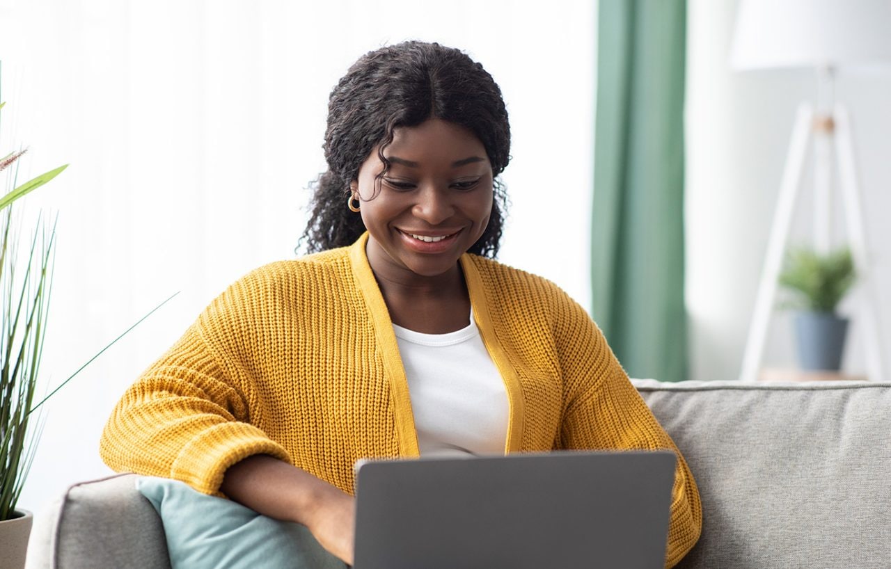 Woman on her laptop sitting on a couch.
