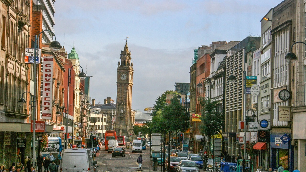 Downtown Belfast indicating shoppers, stores, traffic, cars, and the leaning clock tower.