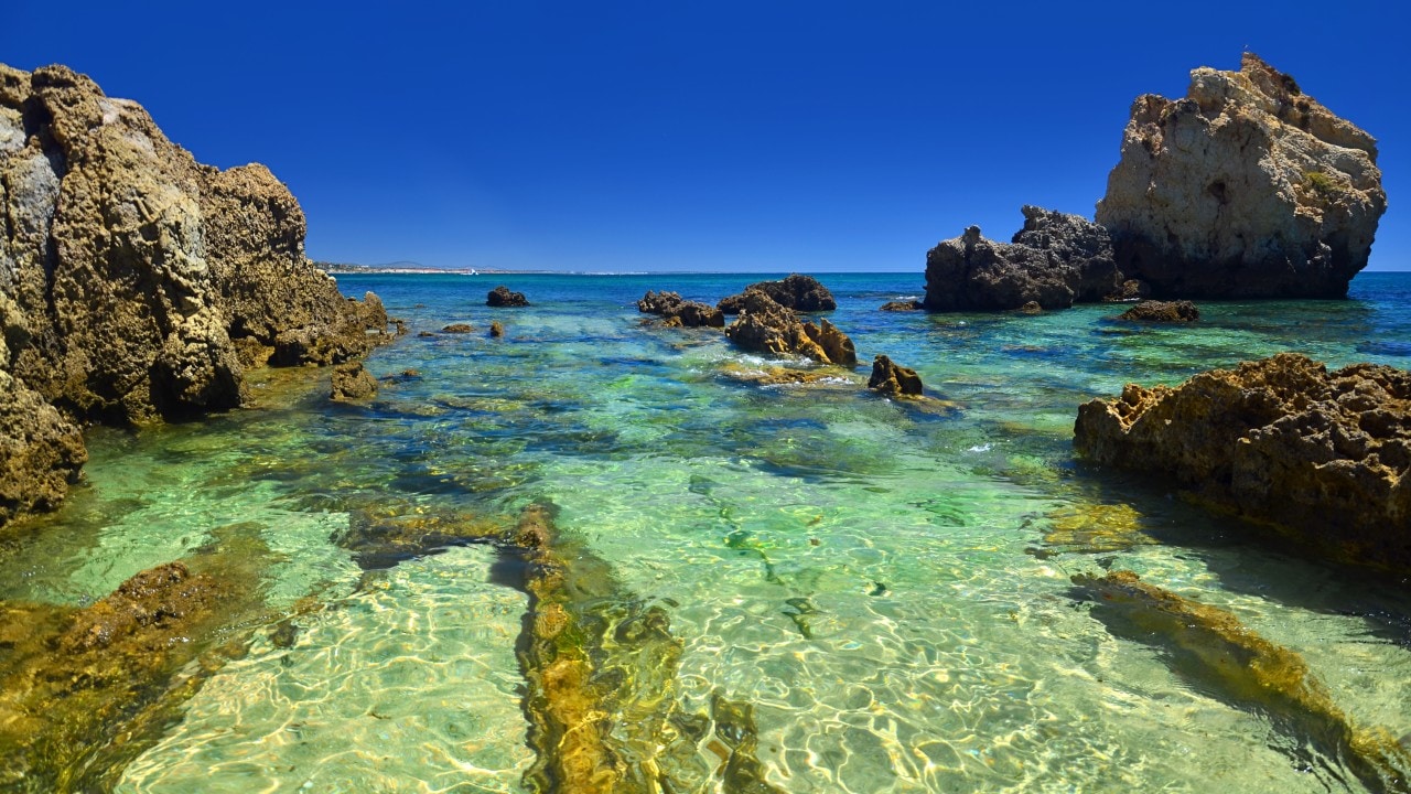 View of the spectacular beach of Arrifes, Albufeira, one of the most beautiful beaches of the Portuguese Algarve, with its imposing cliffs and golden rock formations and its transparent waters, ideal for all kinds of water activities such as snorkeling, kayaking, diving