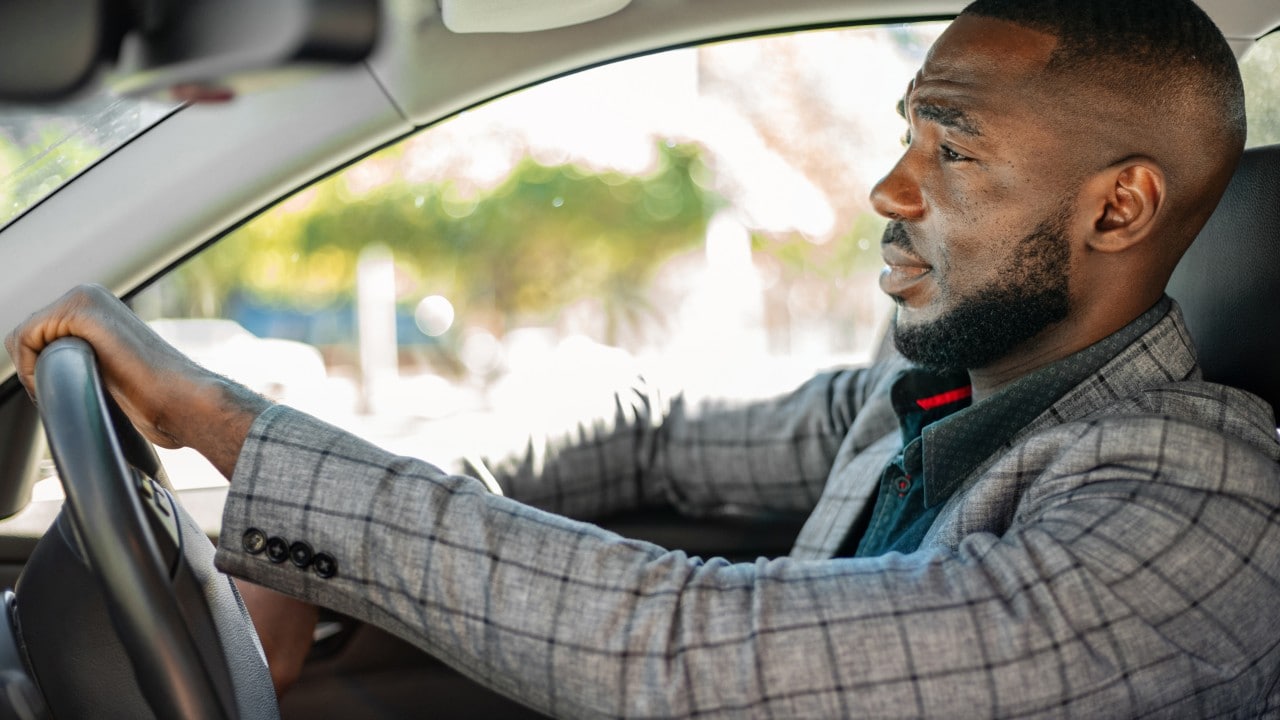 Young African businessman driving car.