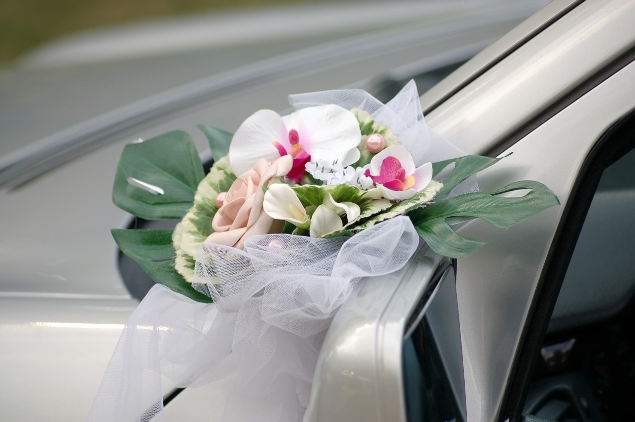 small bouquet of flowers on a mirror of the wedding car